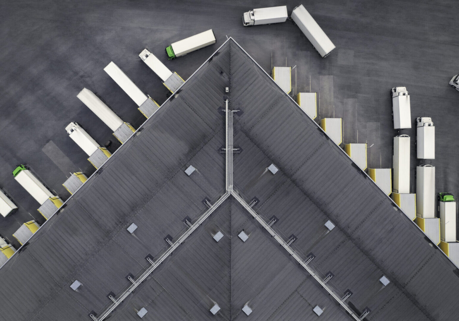Aerial view of a large distribution warehouse with loading docks and many trucks.